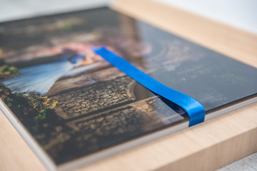 Close up side view of blue ribbon in a tan wooden wedding album box