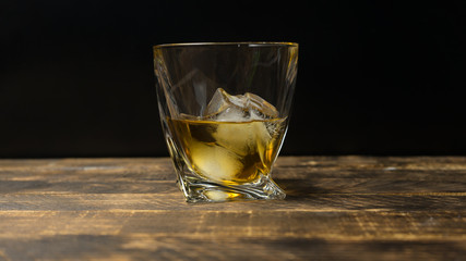 Glass of whiskey on wooden background close up