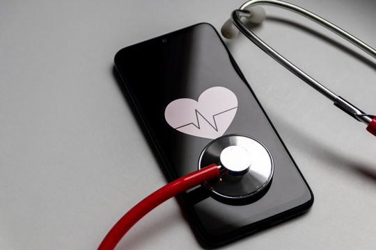 Schwarzes Smartphone mit Herzsymbol und Herzschlag und Stethoskop zeigen digitale Patientenakte, digitale Gesundheitsprogramme und Fitnesstracker in der modernen Gesundheitspraxis