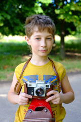 Little boy with an old camera. Young Photographer. Child with retro camera. Cheerful smiling kid...
