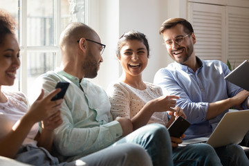 Diverse friends gathered together spend free time with modern devices