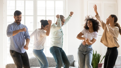Multi racial friends dancing in living room enjoy party together