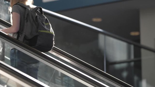 Traveling Woman Riding Escalator Upwards With Backpack At Station