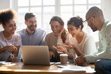Multi-ethnic friends laughing enjoy comedy movie on computer