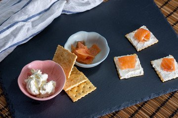 Snack en pizarra con salmón en galleta con queso