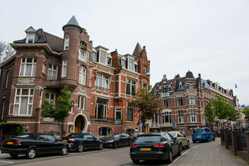 Obraz premium Pejzaż Amsterdamu. Architektura holenderskiego miasta. Nowoczesna fasada budynków. Parkowanie samochodów.
