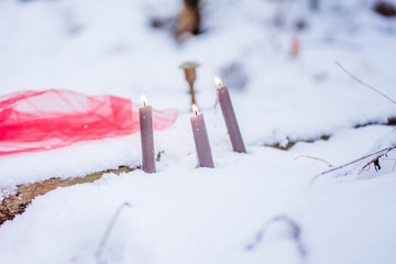 burning candles stand in the snow