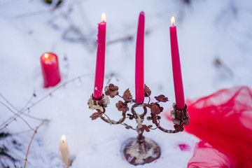 burning candles stand in the snow