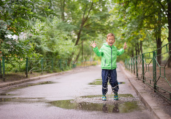 Fototapeta premium cheerful boy jumping puddles with big splash