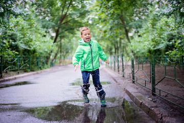 cheerful boy jumping puddles with big splash
