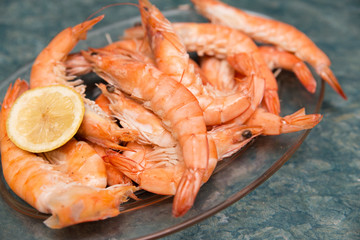 close-up of pile of cooked prawns and a slice of lemon on a glass dish prepared for a celebration