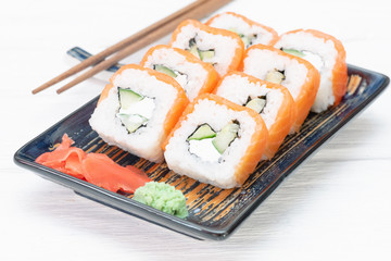 Sushi roll Philadelphia on the plate over white wooden table background.