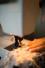 A close-up photo where the seamstress sews lace to the dress.