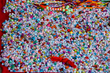 Background of colorful beads for weaving bracelets. Many acrylic cube shape alphabet letter beads. Concept of needlework.