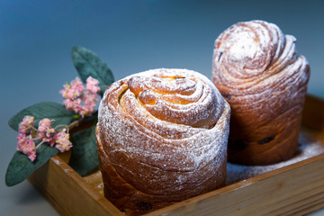 Kraffin (craffin) with powdered sugar on the table. Easter cake and decorative flower.