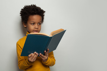 Portrait of little black child boy reading a book on white background