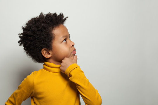 Small black kid boy thinking and looking up on white background