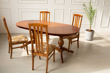 A classic set of wooden furniture for the kitchen. A set of chairs to the table in a classic interior