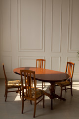 A classic set of wooden furniture for the kitchen. A set of chairs to the table in a classic interior