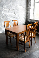A classic set of wooden furniture for the home. A set of chairs to the table in a loft interior room