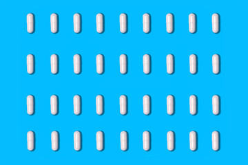white pills arranged in rows on a blue background
