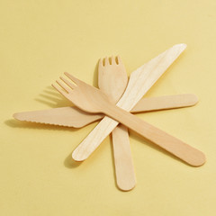 disposable wooden fork and knife on a yellow background