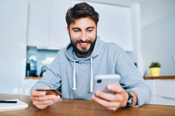 Smiling young man sitting at home and paying online with credit card and smartphone
