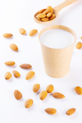 Almond milk with almond on white background. Homemade organic almond milk in a paper cup for healthy breakfast. Vegan milk from almonds nuts in kraft paper cup. Alternative milk. Zero waste