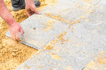 the mason lays gravel slabs on sand to make an alley