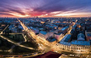 Obraz premium Aerial view of busy city in colorful sunset and street lights. Drone shot of Riga city. 