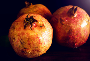 Red saturated pomegranate on a wooden table.