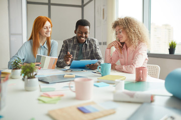 Portrait of multi-ethnic designers team smiling cheerfully while discussing creative project in modern office, copy space