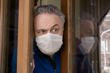 Man with medical mask opens the house door. Coronavirus concept. Respiratory protection. Quarantine...