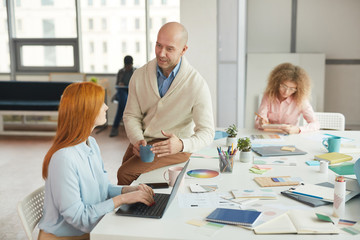 Obraz premium Portrait of balding mature businessman talking to women during coffee break in modern office, copy space