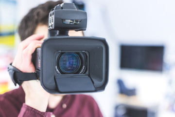 Professional film production: Male filmmaker is recording with a professional movie camera. Close...