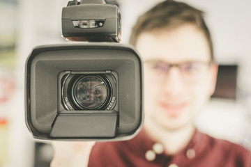 Professional film production: Male filmmaker is recording with a professional movie camera. Close up of camera lens.