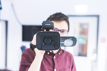 Professional film production: Male filmmaker is recording with a professional movie camera. Close...