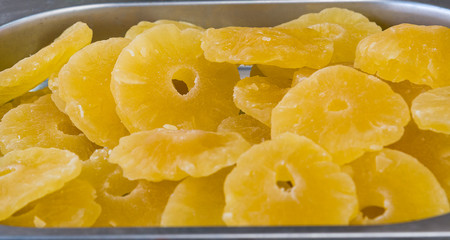 Sweet Pineapple - Dried candied pineapple rings in a full frame composition. Sweet slices of fruit in a warm yellow color under a bright sun on a market stall.