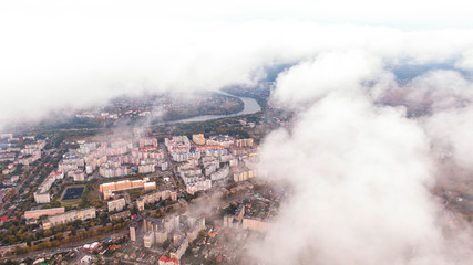 Fototapeta na wymiar City through the clouds. Aerial view of autumn lanscape