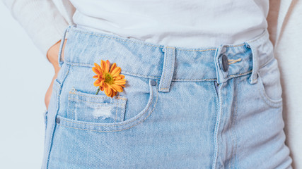 Bright orange flower in pocket blue jeans