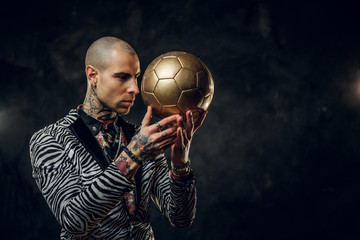 Elegant, masculine, tattooed, bald male model posing in a studio for the photoshoot wearing...