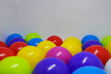 plastic balls of different colors on a white background. dry pool toys