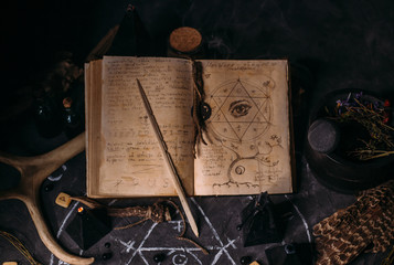 Open old book with magic spells, runes, black candles on witch table. Occult, esoteric, divination and wicca concept. - obrazy, fototapety, plakaty