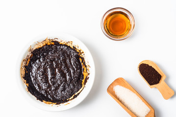 Homemade coffee body scrub made from coffee, sugar and butter in a bowl on a light background