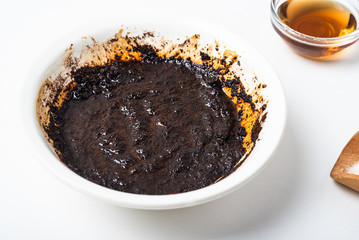 Homemade coffee body scrub made from coffee, sugar and butter in a bowl on a light background