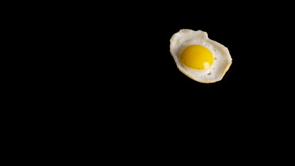 One baked quail egg on a black background. 