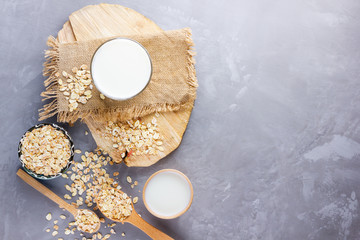 Oat milk. Organic oat milk on a wooden stand. Vegan non-dairy organic drink with oat flakes....