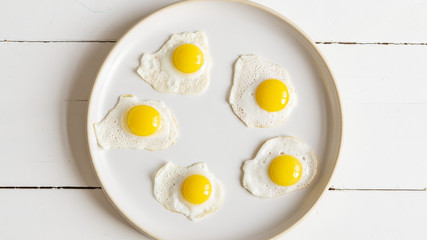 Five baked quail egg on a round plate. White wooden background. 