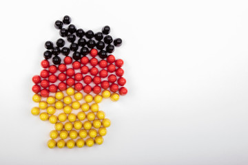 Map of Germany, in national flag colors, build with wooden figurines, white background