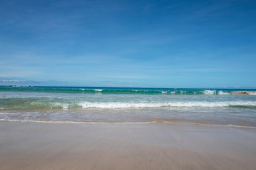 Smooth sand and waves on the beach with a blue sky